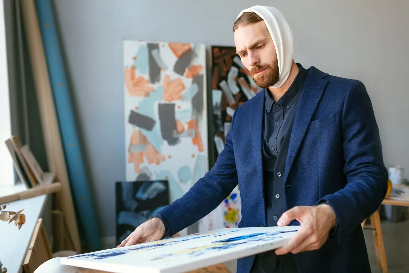 Портрет красивого бородатого мужчины с повязкой на ухе в художественной студии.