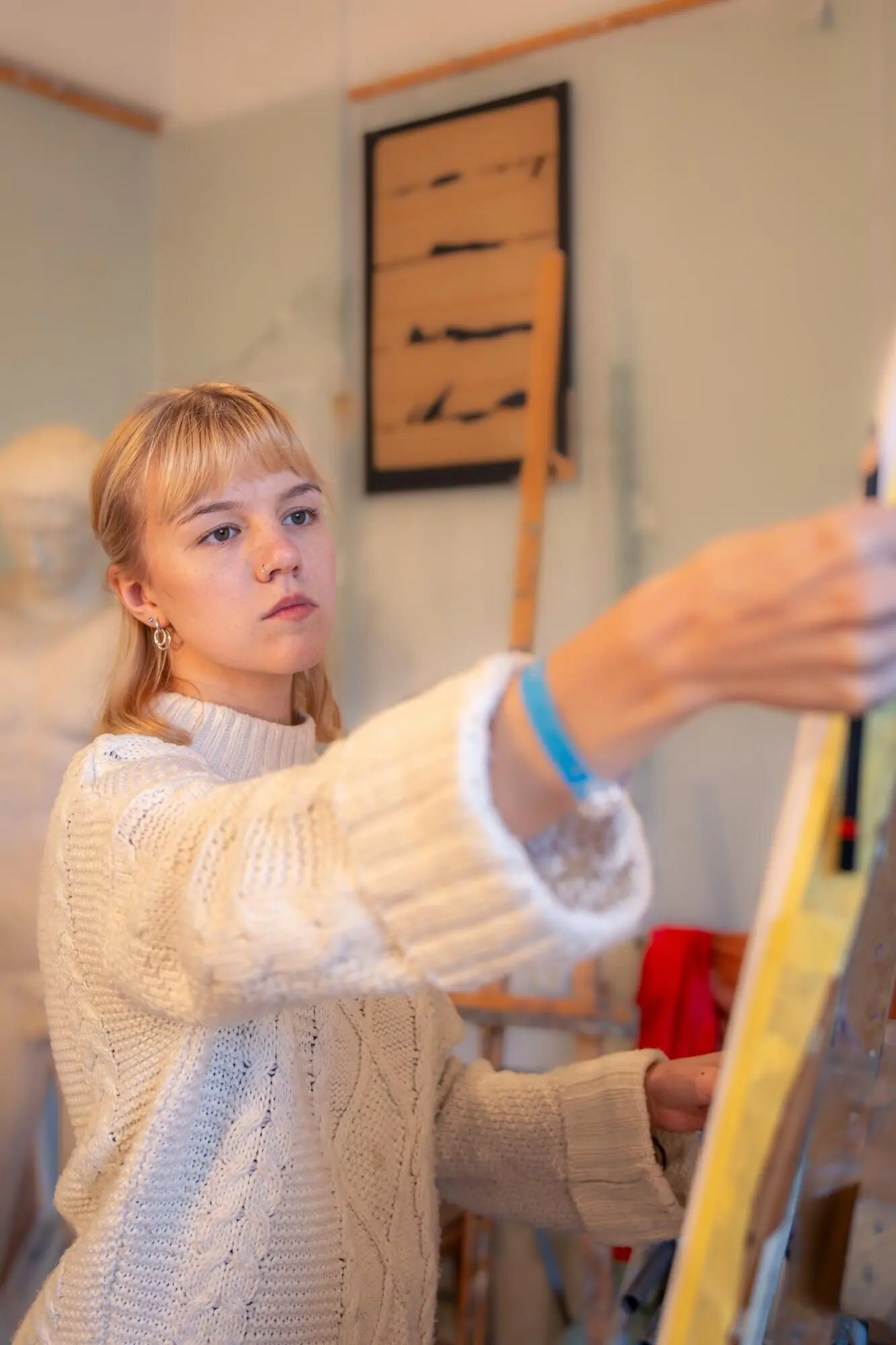 Молодая художница рисует на мольберте в студии. Концепция искусства. Женщина рисует.